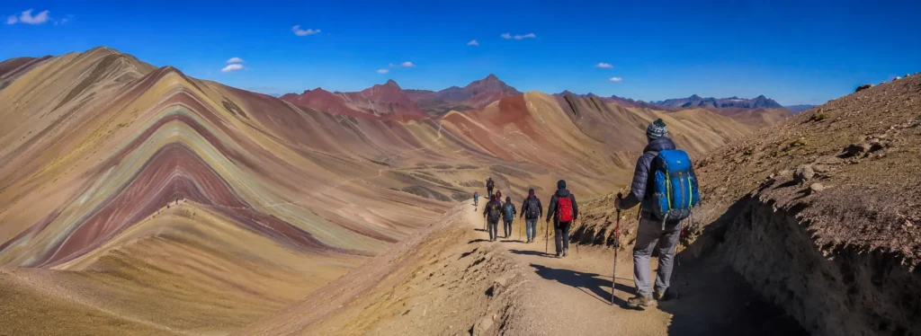 Hikers trekking Rainbow Mountain in Cusco Peru under a clear blue sky – Wonderful Cusco Tours